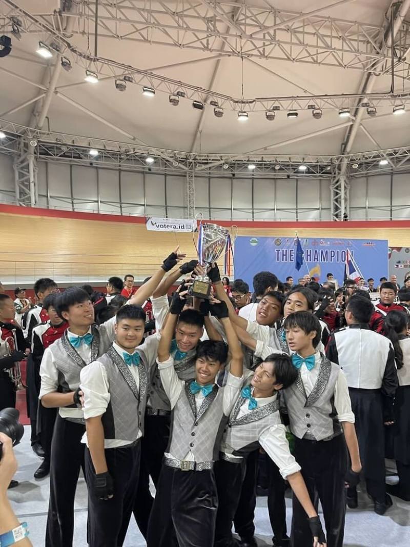 建中樂旗聯隊在「2025世界行進樂旗大賽」中奪下雙冠，學生高舉獎盃開心合影。（建國中學樂旗聯隊家長後援會提供）