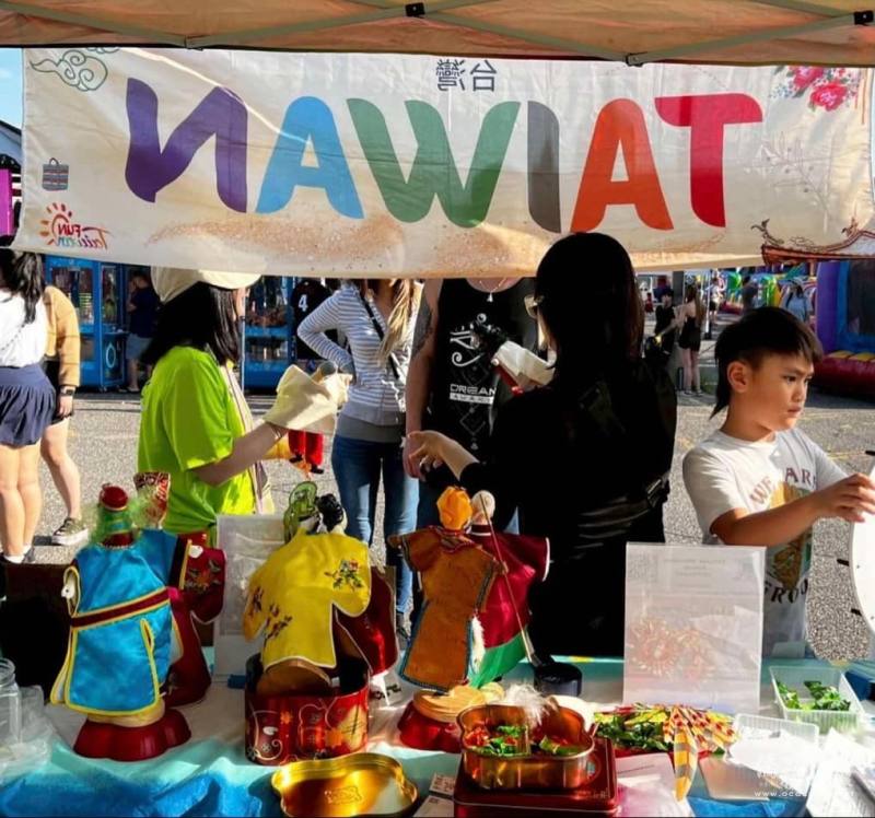 攤位設有趣味互動轉輪和臺灣傳統布袋戲展示，吸引人潮駐足參觀