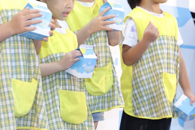 為提升全市學童健康，台北市教育局18日上午在台北延平國小舉辦「鮮奶週報」擴大升級2.0記者會，現場小朋友拿著紙盒牛奶拍照留念。
