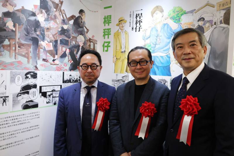 文化部駐日台灣文化中心主辦的年度展覽「多元台灣文化漫畫展」22日在東京正式開幕，駐日代表處副代表周學佑（右）、漫畫家阮光民（中）及文化部駐日台灣文化中心主任曾鈐龍於阮光民作品前合影。（駐日台灣文化中心提供）