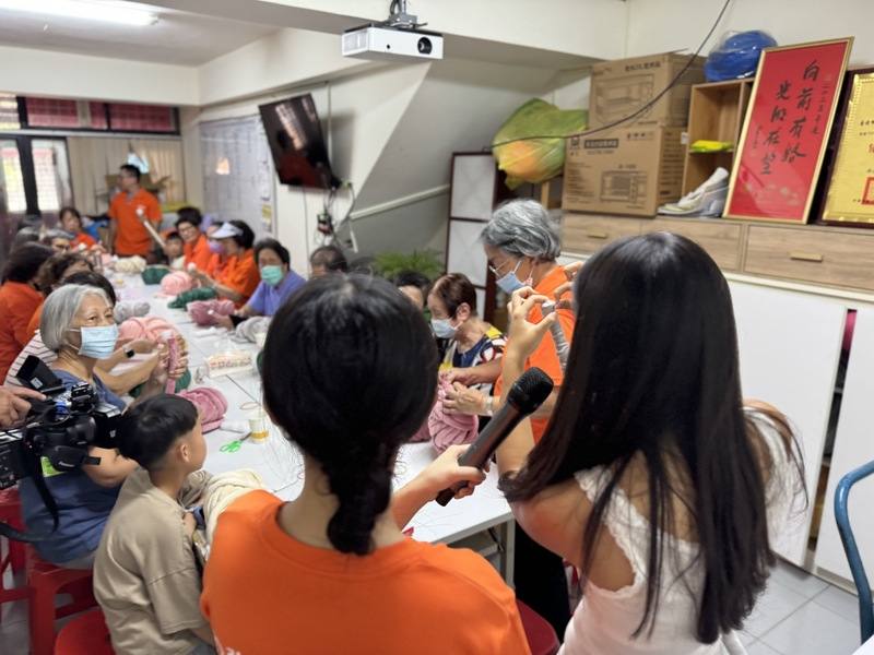 17歲少女Megan（前右）23日擔任弘道老人福利基金會公益教學講師，她拿著冰島粗毛線逐步引導參與長輩製作可愛俏皮的毛線包，場面歡樂溫馨