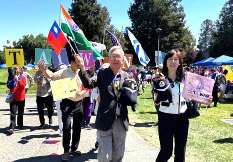 駐舊金山辦事處副處長朱永昌（前排左）、金山灣區僑教中心主任莊雅淑（前排右）帶領下，台僑手舉國旗，及印有台灣、和象徵與各國一起拚的Chip in with Taiwan標語繞行北加州國際童玩節會場。（金山灣區僑教中心提供）
