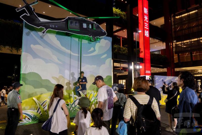 多位民眾排隊與黑鷹直升機「快速繩降」背板合影。（軍聞社記者蔡枋澐攝）
