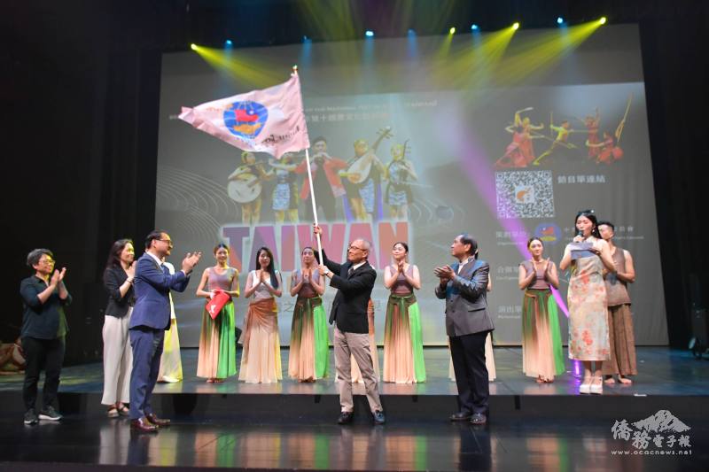 僑委會副委員長阮昭雄授旗予率團團長吳新興，吳新興揮舞會旗