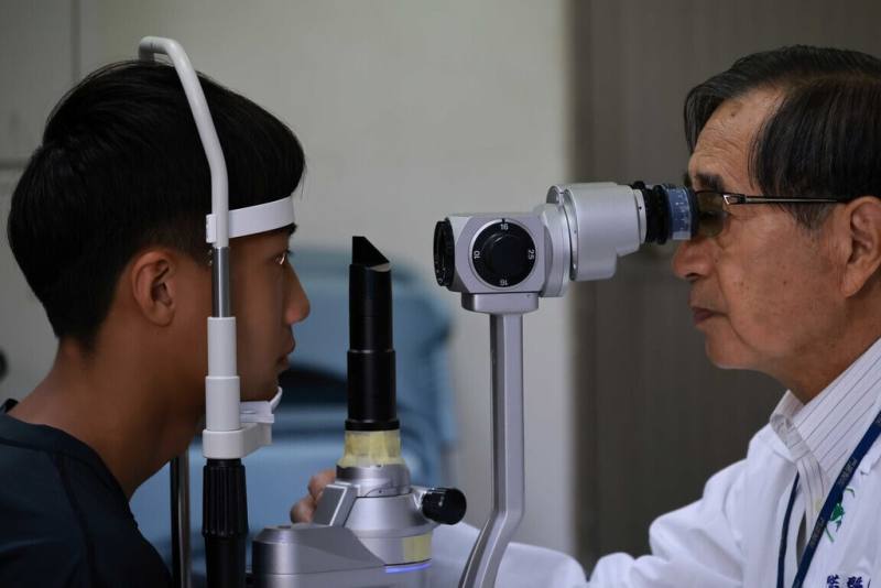 門諾醫院東區視力保健中心與隱形眼鏡品牌業者合作，共推「體育班學生隱形眼鏡視力照護計畫」，免費提供學童近視專用日拋隱形眼鏡，讓選手看得更清晰。圖為門諾醫院副院長許明木（右）為學生檢查視力