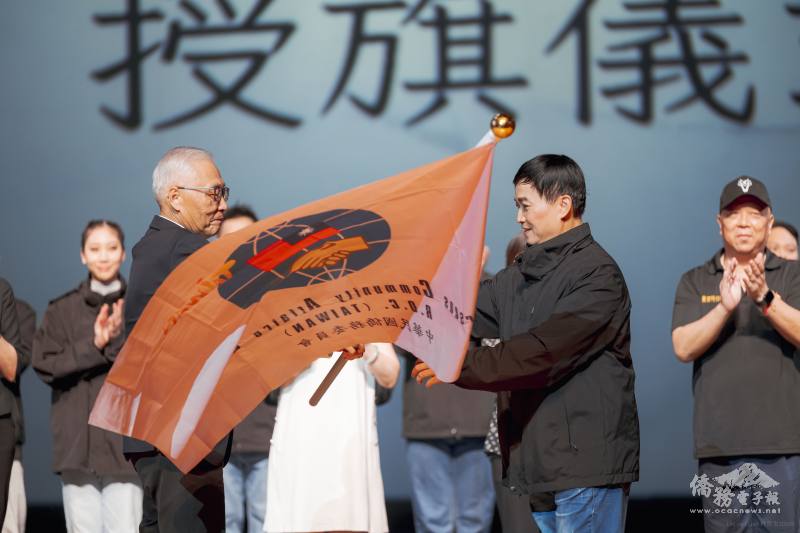 僑委會副委員長張良民授旗予訪問團團長、國立臺灣戲曲學院臺灣特技團副團長王希中(國立臺灣戲曲學院提供)