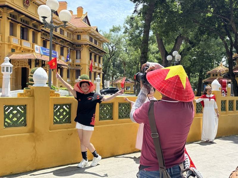 越南將於9月2日迎來獨立紀念80週年，巴亭廣場旁的外交部前許多民眾聚集，想在標誌性的黃色歷史建物前拍照留念，並花錢請現場待命的專業攝影師協助。