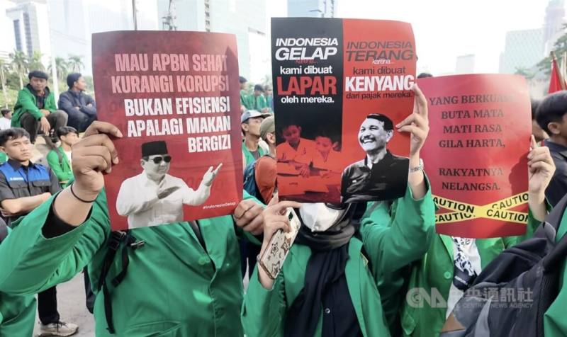 圖為印尼示威學生手舉印有「減少腐敗」字樣與總統普拉伯沃圖像的海報。（中央社檔案照片）