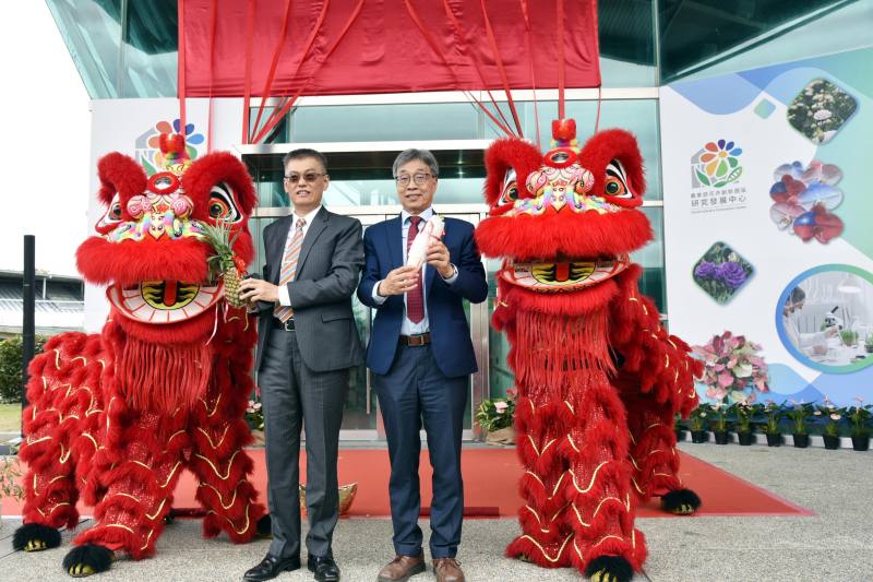 農業部陳駿季部長與花創中心戴廷恩主任手持菜頭及鳳梨，象徵好彩頭