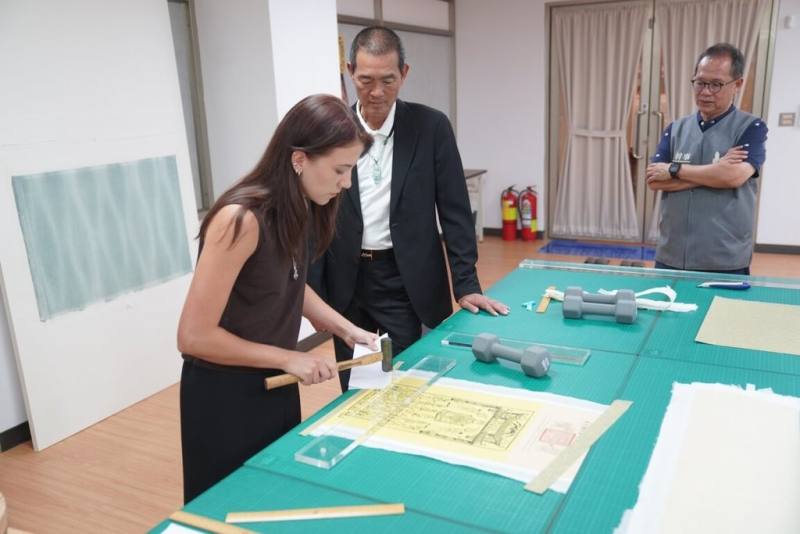 來自法國的書畫修復師迪耶茲（Anaïs Diez）（左）目前正在北港朝天宮文物修復中心進行紙質文物修復技術交流活動，朝天宮董事長蔡咏鍀（左2）4日現場參觀了解紙質文物修復過程。（北港朝天宮提供）