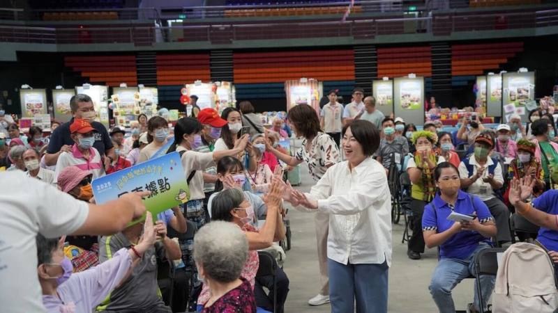 屏東縣政府長照處5日在屏東縣立體育館舉辦「2025屏東樂智嘉年華」，縣長周春米（前白襯衫者）出席，與長輩們近距離聊天、互動。（屏東縣政府長照處提供）