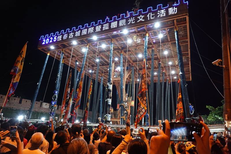 屏東縣恆春鎮一年一度的豎孤棚搶孤活動6日中元節晚間在東門廣場登場，17支隊伍以疊羅漢方式競技，力拚攻頂敲鑼奪順風旗，場面相當熱鬧