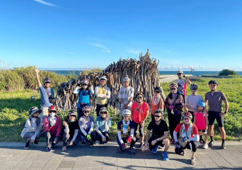 推廣單車低碳遊，北海岸及觀音山國家風景區管理處13日舉辦「2025極北點富貴角燈塔騎跡」單車慢旅活動，參與車友在途中行經的裝置藝術前合影留念。（北海岸及觀音山國家風景區管理處提供）