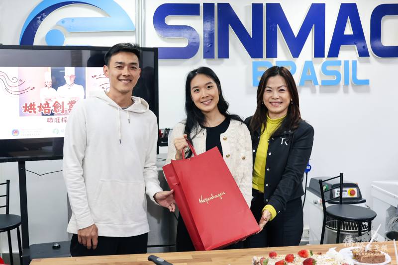 巴西臺灣青商會會長簡俞育（左）及秘書黃麗縝（右）一同贈送禮物給郭憶憶（中）