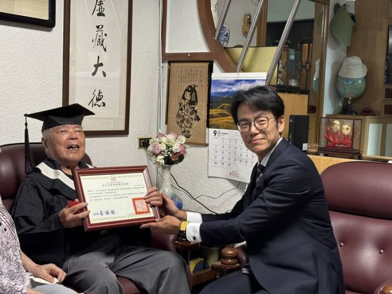 白色恐怖受難者趙清淵（左）16日接受淡江大學學生事務處生活輔導組組長虢恕仁（右）頒贈榮譽畢業證書，並獲贈1套文學院學士袍，完成專屬於他的畢業典禮。（人權館提供）