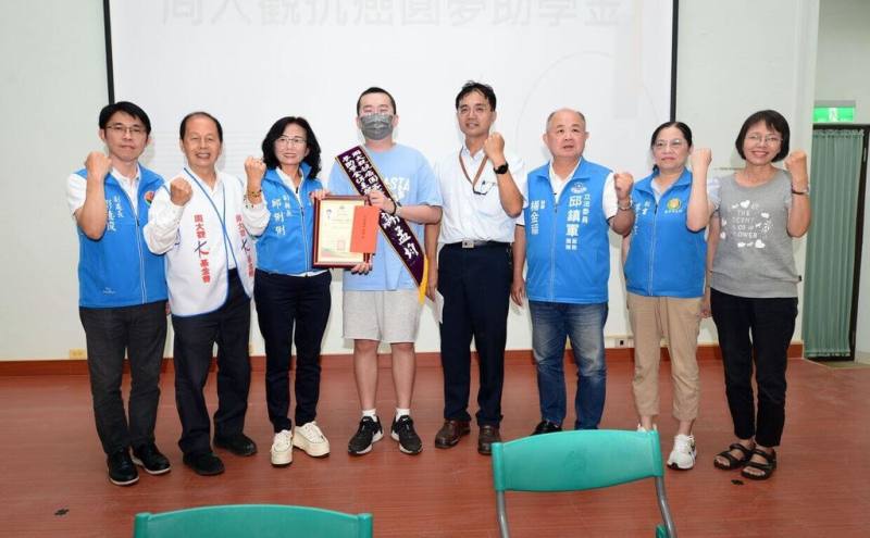 苗栗高中畢業生謝孟均（左4）於大學甄選期間被診斷罹患血癌，抗癌期間仍精進客語朝夢想前進，17日獲周大觀文教基金會頒發抗癌圓夢助學金，基金會創辦人周進華（左2）、苗栗縣副縣長邱俐俐（左3）、苗中校長巫正成（右4）等人為他加油打氣。（苗栗縣政府提供）