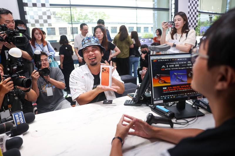 台灣大哥大19日在台北舉辦iPhone 17新機首賣會，「頭香」工程師黃先生開心地拿著「宇宙橙」新機接受媒體拍攝