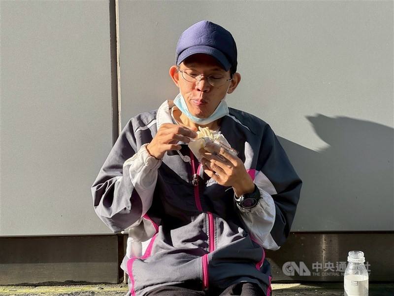 Chang Yun-hsiang, a 39-year-old homeless man, eats a sandwich that he managed to buy for breakfast, on a street near Taipei Main Station. CNA photo Sept. 20, 2025