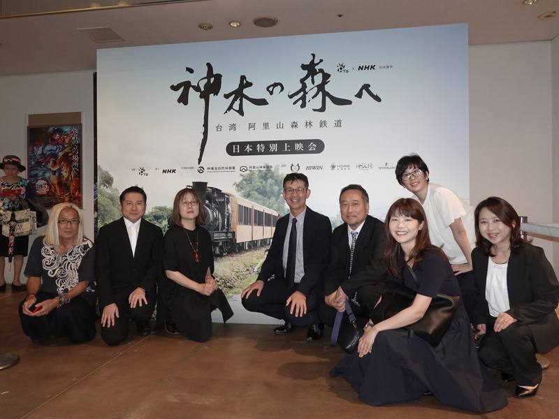 台灣公共電視與日本放送協會（NHK）共同製作紀錄片「神木之森：阿里山森林鐵道紀行」21日在東京舉行特映會，日方製作團隊在看板前合影，包括NHK國際合作首席製作人柴崎壮（前排右4）、導演安藤良美（左3）、NHK展開中心展開推進部長加藤拓（前排右3），以及負責配樂、國際知名作曲家吉田潔（左1）。