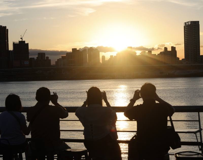 秋分時太陽直射赤道，白天夜晚時間相當，過了這一天白天將越來越短。圖為傍晚時分氣溫稍降，民眾在台北大稻埕碼頭拍攝夕陽美景。（中央社檔案照片）