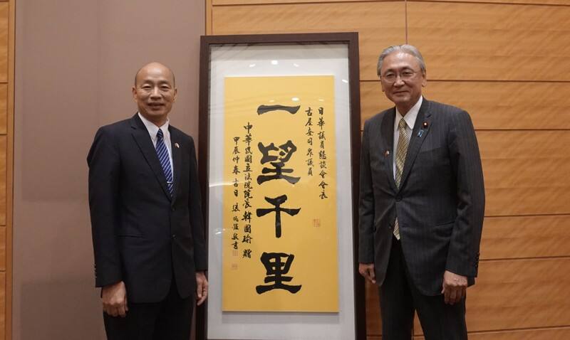 立法院長韓國瑜（左）率領跨黨派立委訪問日本，25日傍晚拜會日華議員懇談會，與日華懇會長古屋圭司（右）在書法大師張炳煌揮毫寫著「一望千里」的墨寶前合影。這是立法院副院長江啟臣去年訪日時，代表韓國瑜贈送古屋的作品。