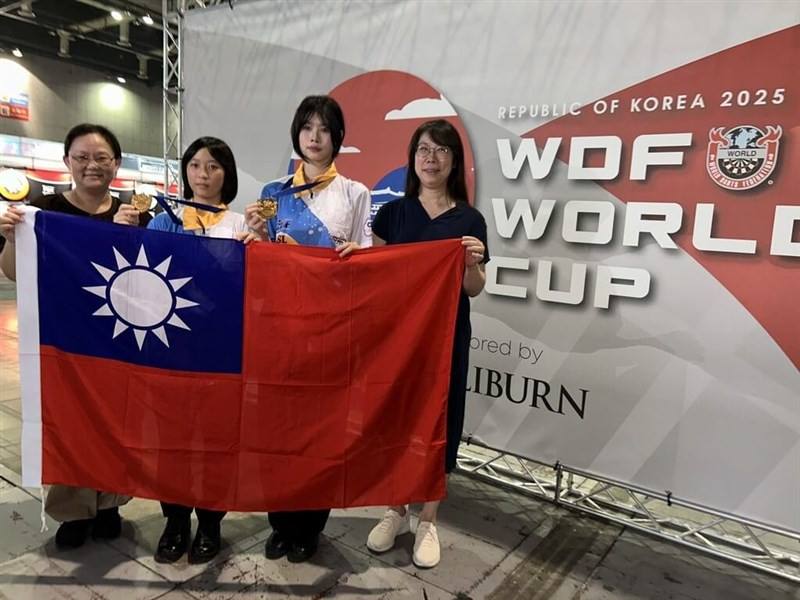 Taiwan's U-18 darts players Tsai Yung-en (second left) and Yang Yi-ching (second right) display the flag of the Republic of China (Taiwan) with their chaperones after winning the 2025 WDF Girl's Best Champions title on Friday. Photo courtesy of the Chines