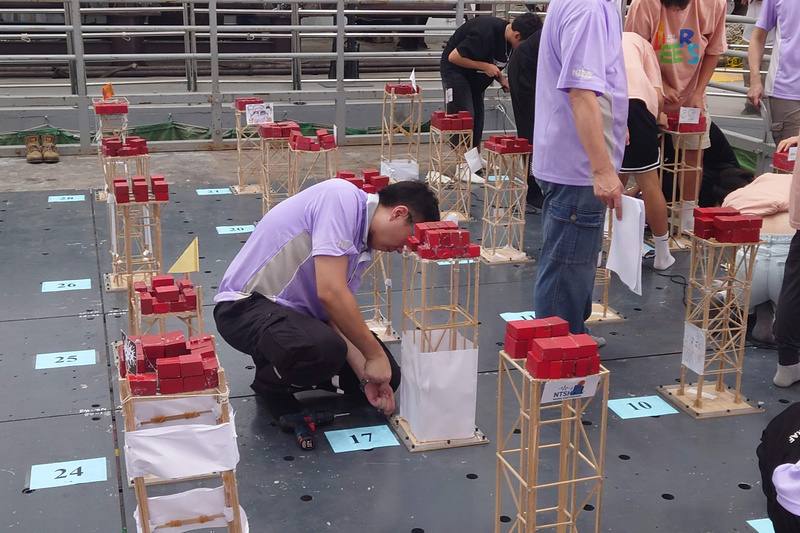 國家實驗研究院國家地震工程研究中心1日在台南實驗室舉辦地震工程模型製作國際競賽，工作人員協助將參賽作品固定於振動台