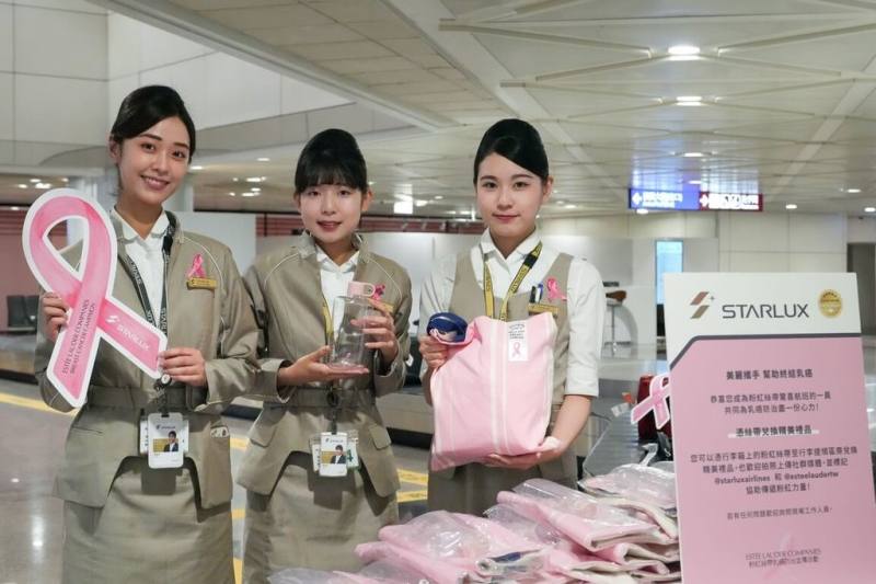 星宇航空2日攜手雅詩蘭黛集團與桃園國際機場公司，在桃園國際機場第二航廈入境行李提領區規劃快閃活動，由工作人員為抵台旅客行李繫上巨大紙製粉紅絲帶，除可兌換專屬托特包及水壺，也鼓勵旅客拍照分享至社群平台，傳遞粉紅驚喜正能量。（星宇航空公司提供）