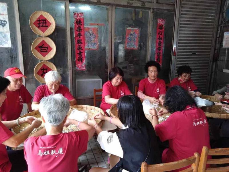 114年馬祖秋慶系列活動「鐵板燒塔節」11日將在南竿鄉仁愛村登場，活動中包含「白丸」廚藝競賽，而「白丸」為馬祖特有點心，可長期保存，但成形與烹煮皆須一定技術。圖為村民齊聚「扭白丸」。（鐵板社區發展協會提供）