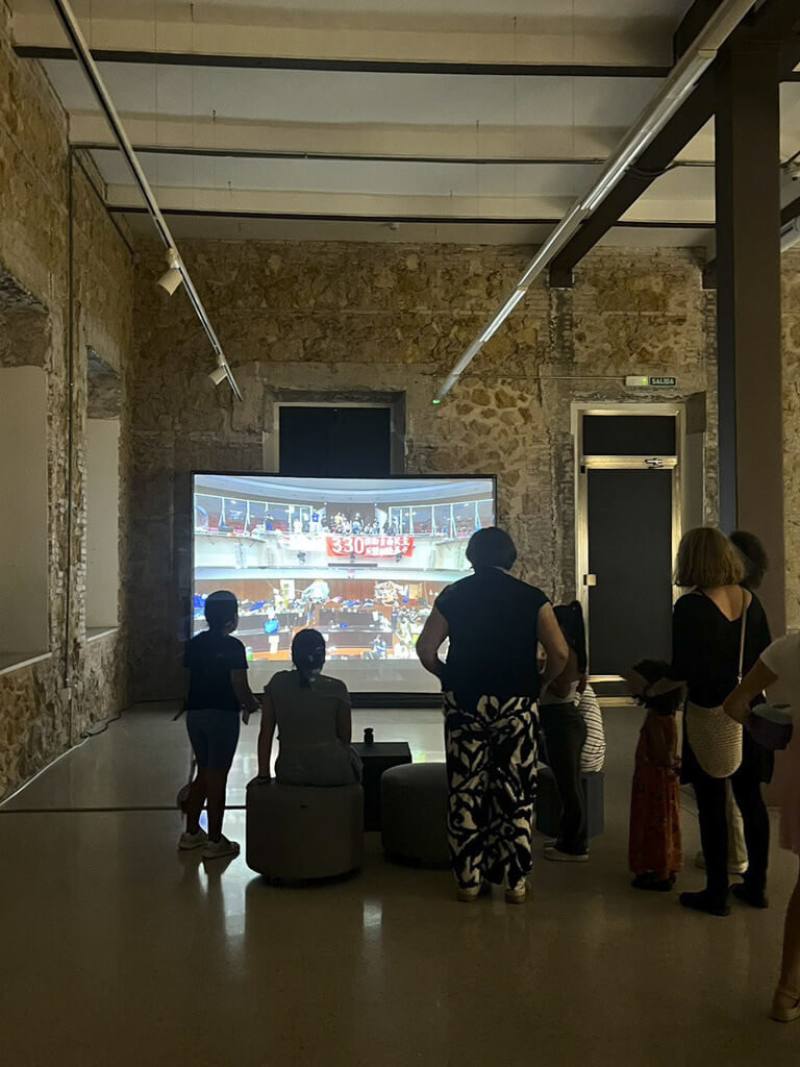 「臺灣回聲」數位藝術專題展覽10月3日至11月14日舉行，是台灣藝術首度拓點至西班牙東南部沿海城市穆西亞，駐西班牙代表處文化組期望藉由8位藝術家的獨特視角，展現台灣藝術觀點及政治文化脈絡，促進台西文化交流。圖中背景錄像作品為藝術家袁廣鳴記錄2014 年太陽花學運撤場前夕場景的「佔領第561小時」。（駐西班牙代表處文化組提供）