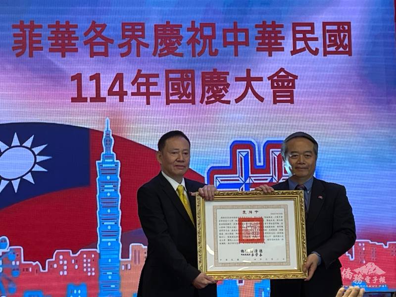 駐菲代表大使周民淦(右)代表中華民國政府頒發李永年總統褒揚令，由家屬李民勇(左)接受。