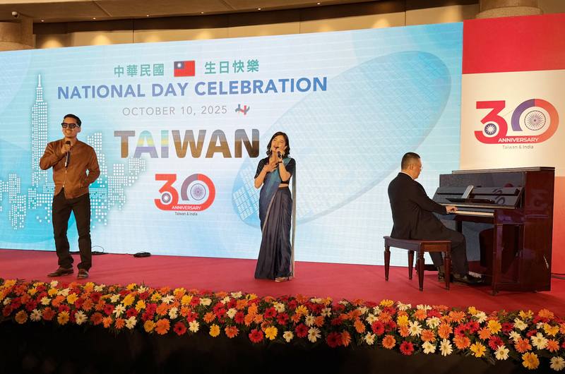 駐印度代表處8日在新德里舉辦國慶酒會。印度歌手、駐處官員上台合唱組曲，副代表謝柏輝（右）展現琴藝，為上台演唱者伴奏，現場帶起一波高潮