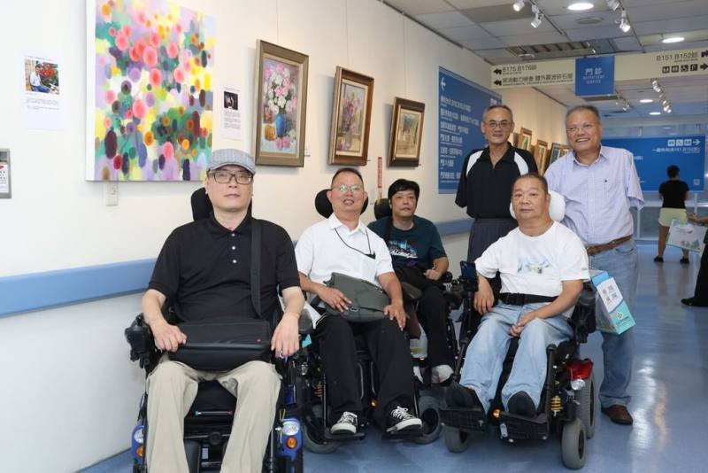 童綜合醫院在轉角藝廊舉辦「彩繪生命 口足畫家繪畫聯展」共展出40幅作品，展出畫作的口足畫家們。（童綜合醫院提供）