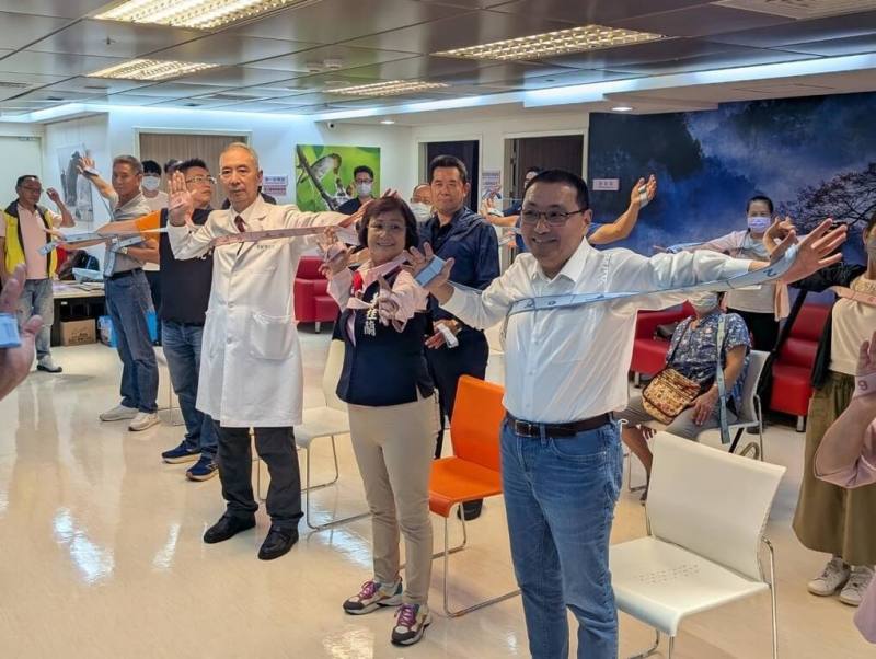 新北市長侯友宜（前右1）16日前往新北市立聯合醫院三重院區訪視關懷農漁民長者健康檢查，與農漁民一起體驗彈力帶伸展樂活操，並宣布115年起加碼100%補助農民職業災害保險保費。（新北市農業局提供）