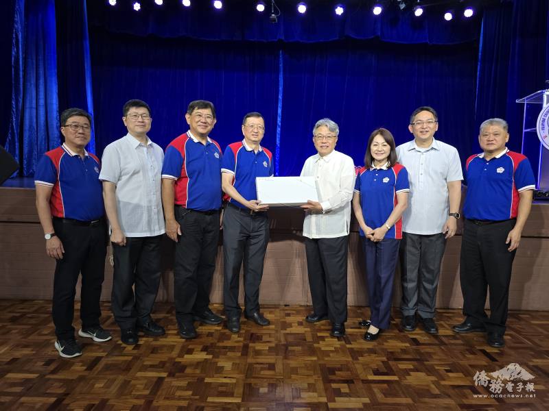 楊登仕（右4）贈送紀念品予菲華文經總會，並由陳柏材（左4）代表接受