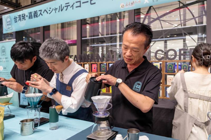 嘉義縣府與11家咖啡莊園業者即日起在日本大阪近鐵百貨設置專區，展售產自阿里山區的精選精品，18日縣長翁章梁（左3）在現場手沖咖啡，供日本消費者試飲。（嘉義縣政府提供）