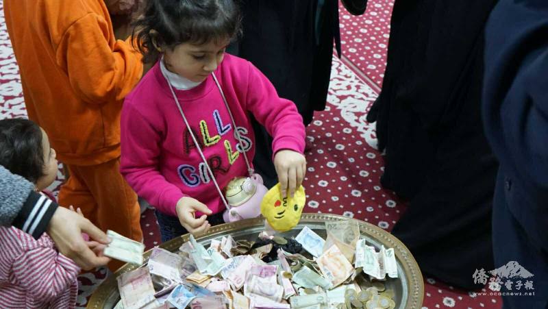 孩童們在家長陪同下將錢包裡的零錢投入募款盤，純真的微笑象徵希望與關懷，也傳遞「從小行善」的教育精神。