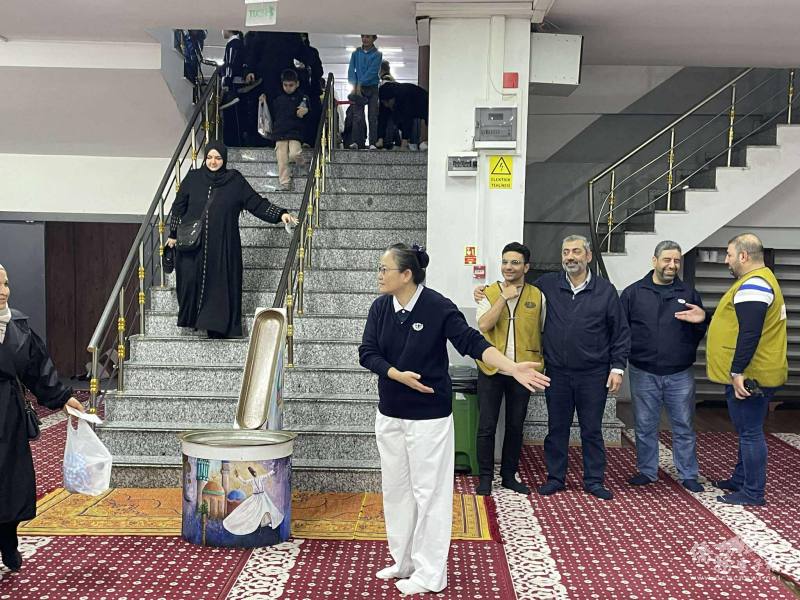 志工們在樓梯口協助引導鄉親，滿納海學校禮堂洋溢著秩序與溫情。每一位來到現場的家庭，都能感受到慈濟志工如家人般的關懷與尊重。