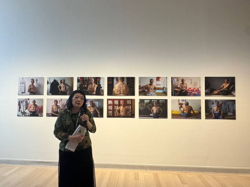 策展人胡永芬介紹攝影師黃子明關注以生命刻畫戰爭傷痕的系列作品「韓戰反共戰俘的政治紋身」。（駐捷克文化組提供）