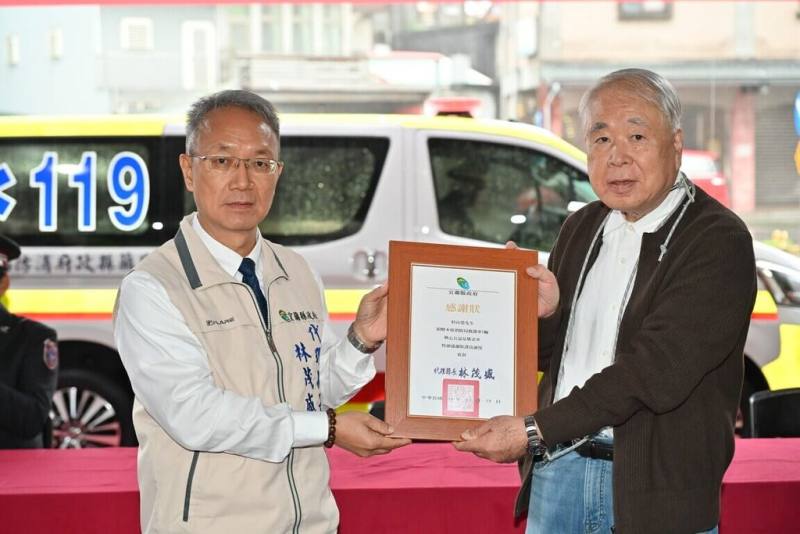 日籍人士杉山榮（右）曾在台灣日商公司任職，感念台灣完善醫療救護體系，他19日捐贈1輛救護車給宜蘭縣消防局，盼協助更多有需要的病患，代理縣長林茂盛（左）回贈感謝狀。（宜蘭縣政府提供）