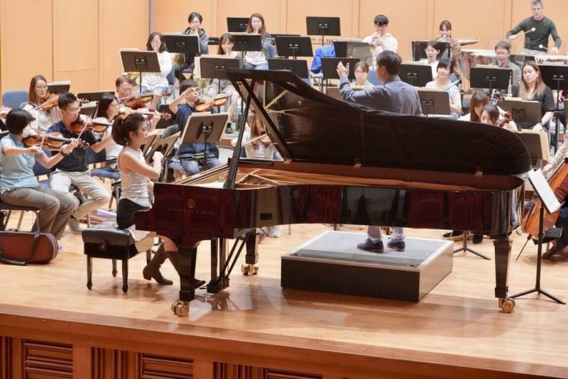 國立台灣交響樂團首席客席指揮水藍（前右背對立者）與鋼琴家陳毓襄（前左）2度合作，將於台中、高雄帶來國台交80週年團慶音樂會。圖為樂團排練情形。（國台交提供）