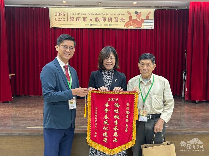 清平民立華文學校校長廖子權（圖左）及啟秀華文中心校長林興（圖右）致贈錦旗及紀念品，僑務委員會僑教處處長林季蓉（圖中）代表接受