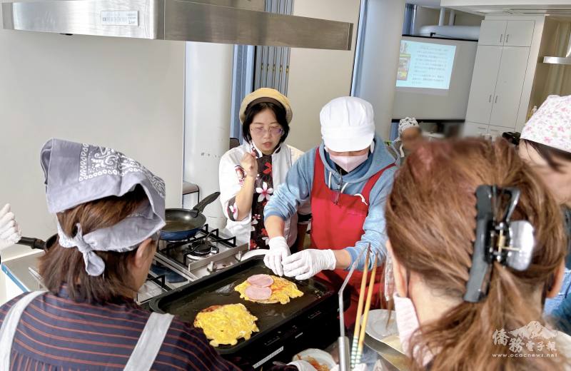 陳洳豔指導煎蔥油餅技巧，參加者圍繞操作臺一同練習