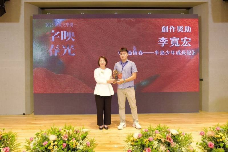 來自恆春的李寬宏（右）6日在2025屏東文學獎頒獎典禮接受屏東縣長周春米（左）表揚。他以作品「風過之地」獲散文首獎，並以「風過恆春－半島少年成長記」獲創作獎助金。（屏東縣政府文化處提供）