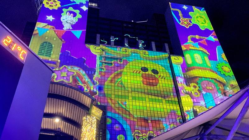 2025新北歡樂耶誕城持續開城，6日週末夜現場人潮滿滿，最新的雷射光雕投影秀以「馬戲團魔法道具篇」為主題，LINE FRIENDS人氣角色莎莉不時現身，吸引民眾目光。