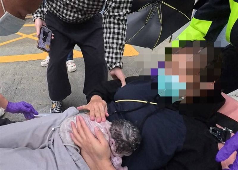 A mother holds her newborn after giving birth on a roadside in northeastern Taiwan’s Yilan County on Wednesday. Photo courtesy of Yilan County's Fire Bureau