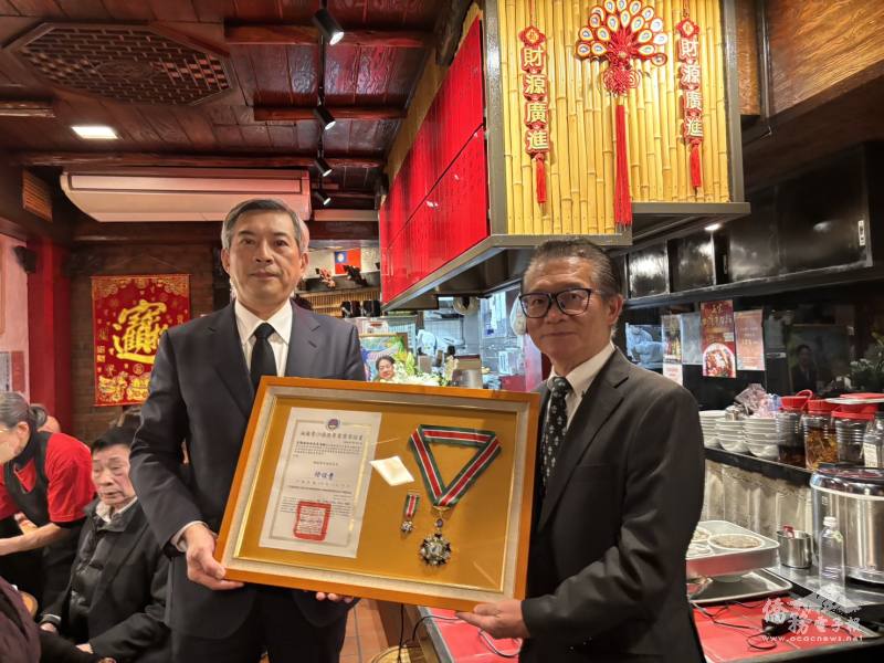 駐日代表處公使周學佑（左）代表頒贈福爾摩沙僑務專業獎章予莊海樹長子莊光泰欽（右）