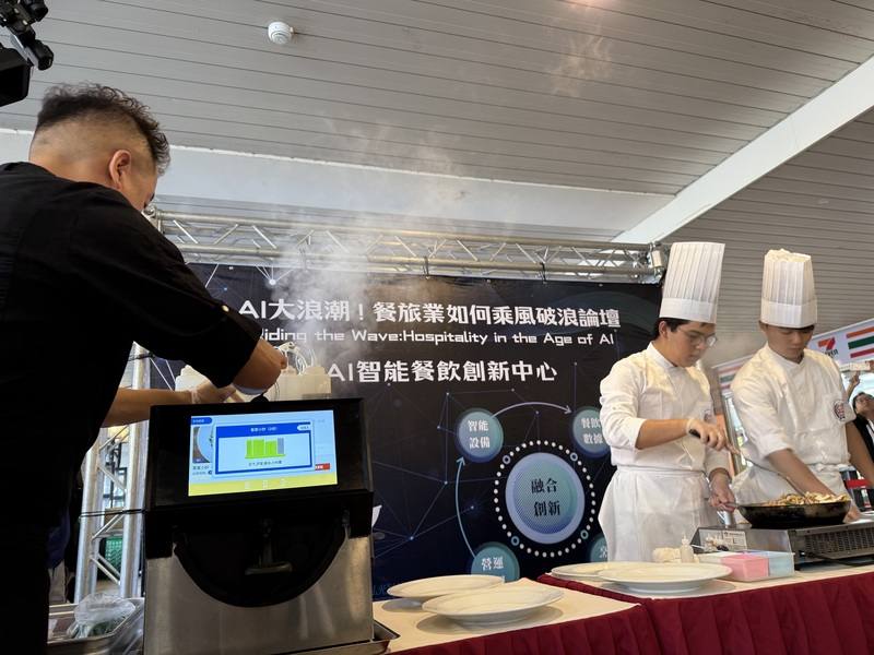 弘光科技大學12日舉辦「AI大浪潮！餐旅業如何乘風破浪」研討會，由真人廚師與AI智能廚師比賽客家小炒，工作人員將材料倒進智能炒菜機中烹調，智能廚師僅以4分鐘完成菜品