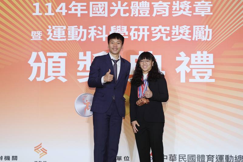 舉重女將陳冠伶（右）在多個國際賽事表現亮眼，11日於114年國光體育獎章暨運動科學研究獎勵頒獎典禮中，由運動部長李洋（左）頒發12面國光獎章