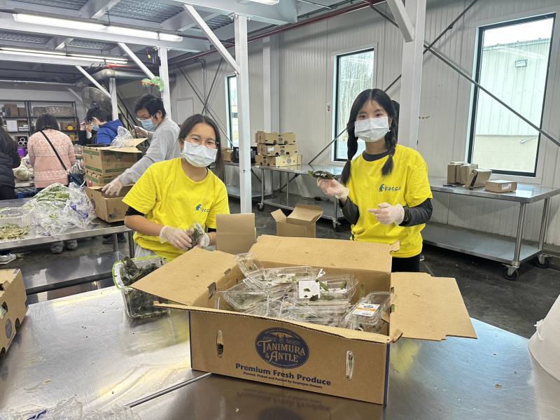 Two FASCA members throw away food containers after sorting the items.